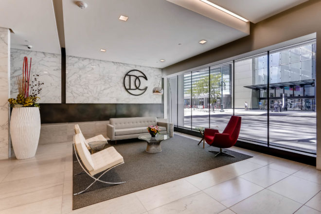 The new mid-century-modern lobby at the DC Building features modern furniture, marble walls, and the buildings "DC" logo