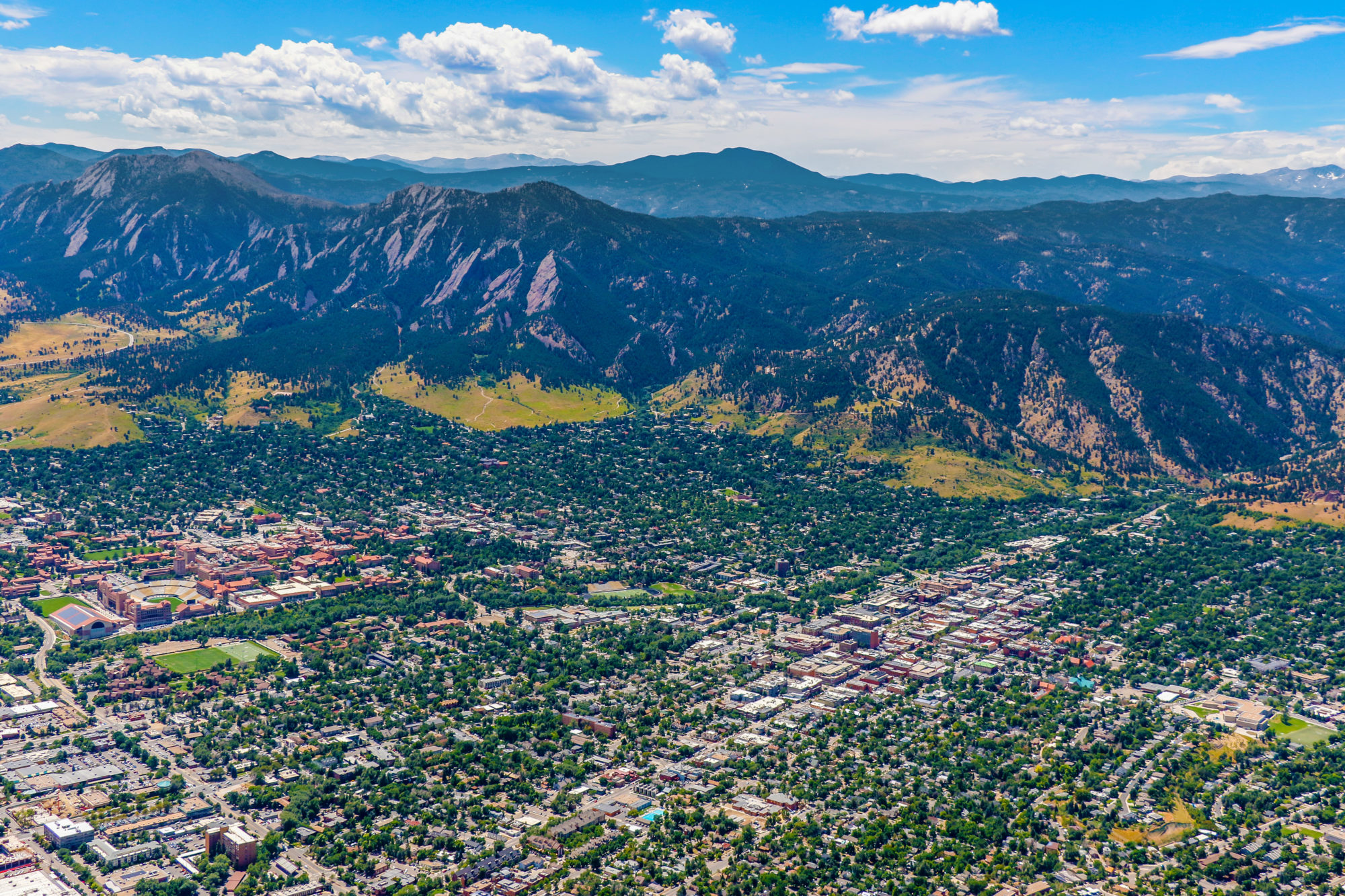 Aerial view of downtown Boulder and the Rocky Mountains, with Pearl Street Mall and the CU Boulder campus visible.