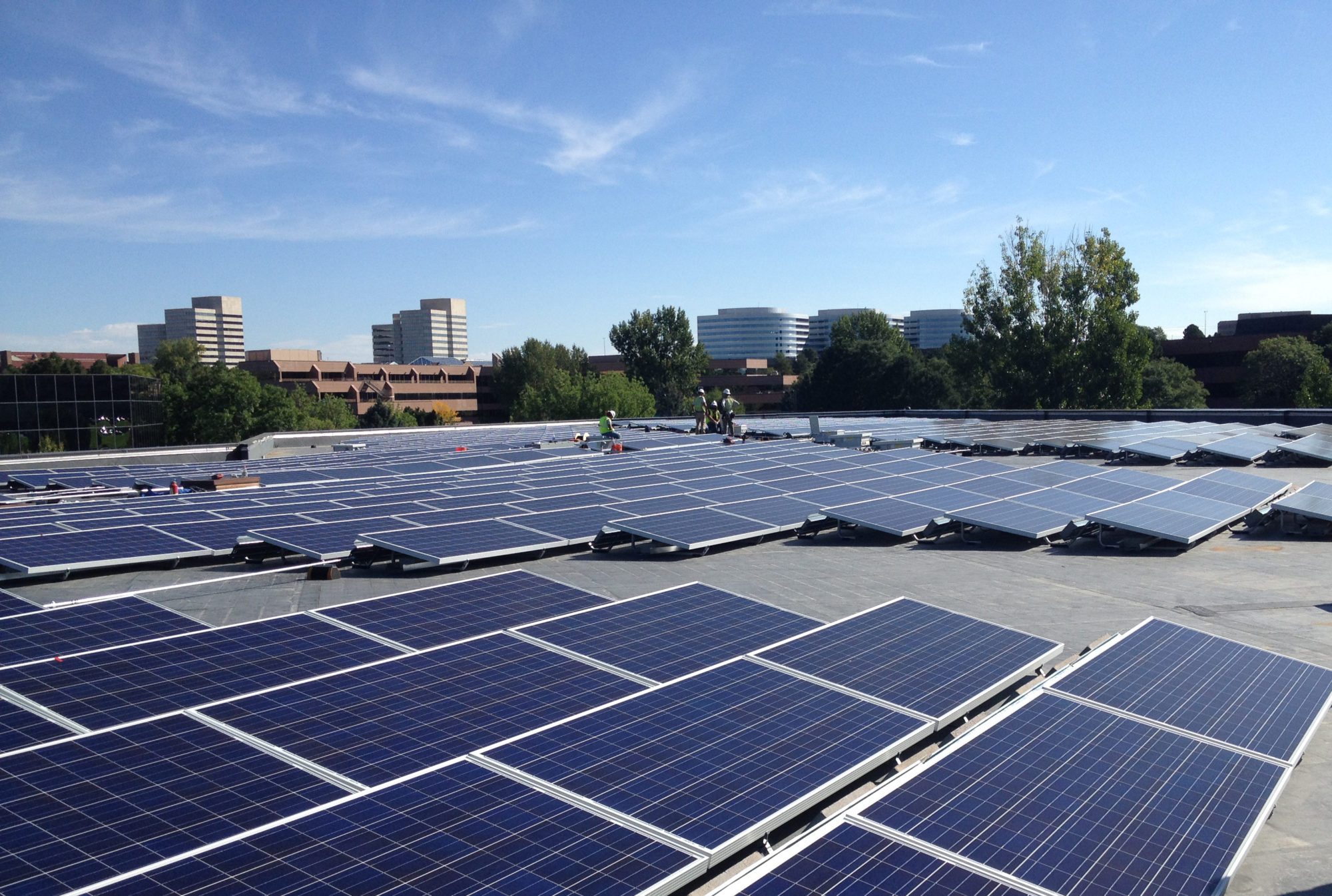 Workers install solar panels on the roof of Harlequin Plaza in Denver, Colorado.