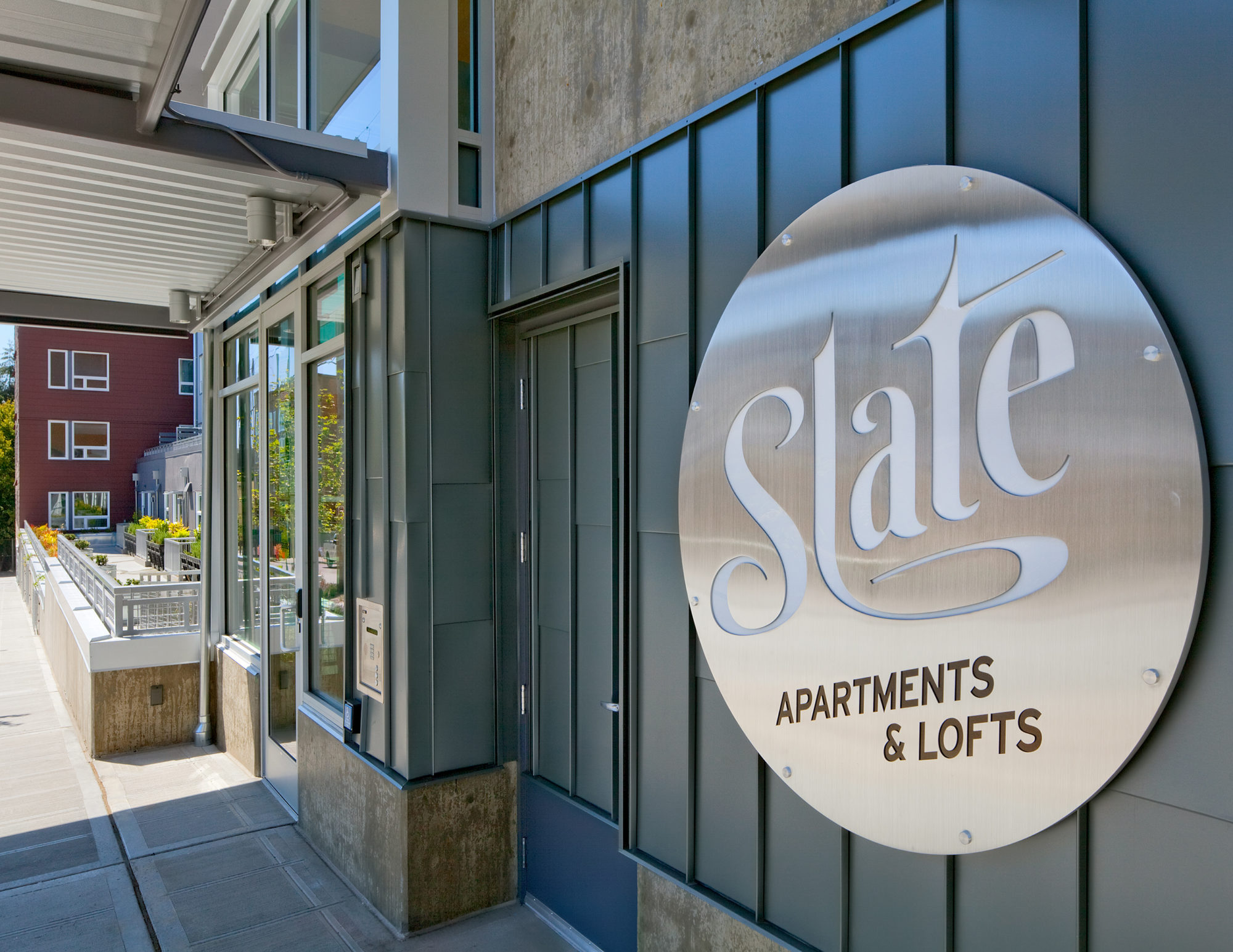 Circular metal sign with the words "Slate Apartments & Lofts" engraved upon it.
