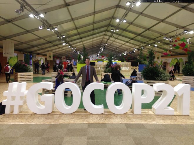 Unico Solar Investors Director Brett Phillips in front of a large #GOCOP21 sign at the COP21 conference in Paris 2015