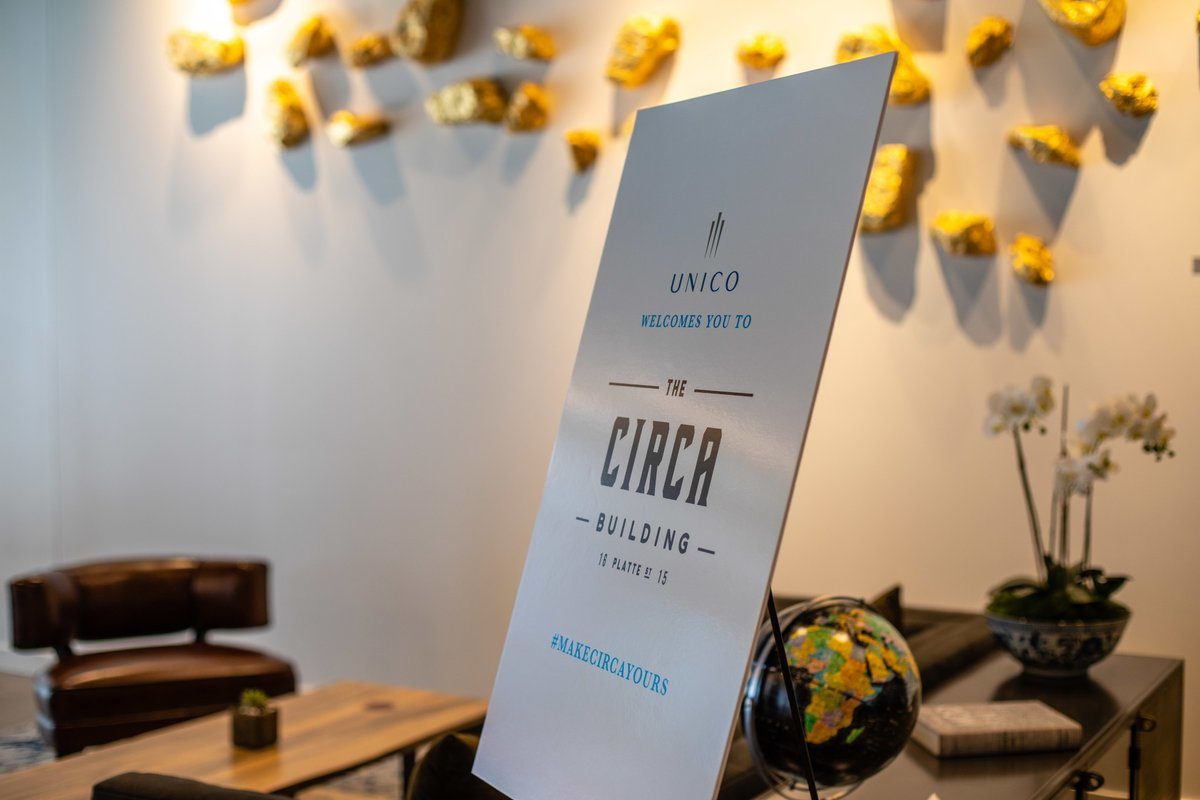 Unico Properties, a commercial real estate investment firm, celebrated the opening of Circa Building. Circa is a LEED Platinum-certified building rising above Platte Street. A poster welcomes attendees in the lobby of Circa. The text reads "Unico Welcomes You To The Circa Building" and includes the hashtag #MakeCircaYours.