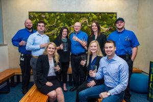 Employees of Unico Properties, a private equity real estate investment firm, posing with glasses of purified rainwater for a group shot at the Bullitt Center's lobby.