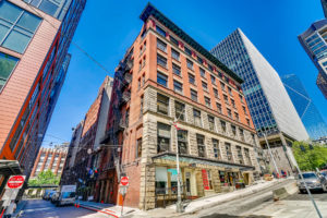 View of Post Alley in this exterior photograph of the Colman Building, a historic City of Seattle landmark located in Seattle's Waterfront. The commercial real estate investment company Unico Properties acquired the asset in May 2019.